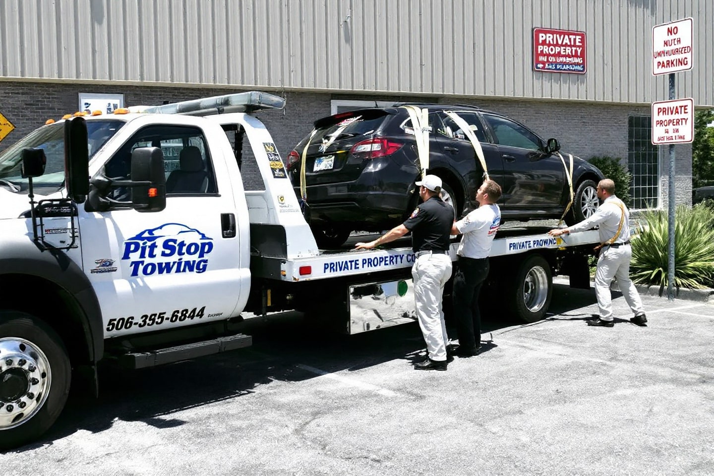 Pit Stop Towing team performing private property towing, securing a vehicle on a flatbed truck in a marked private property area.